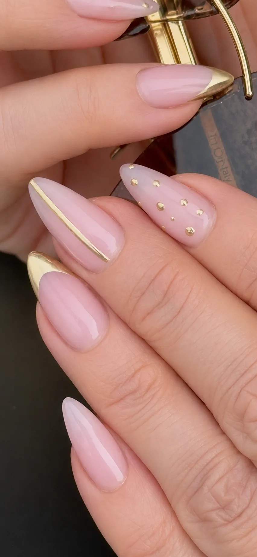 Milky-pink almond nails finished with gold chrome accents and fine gold studs.